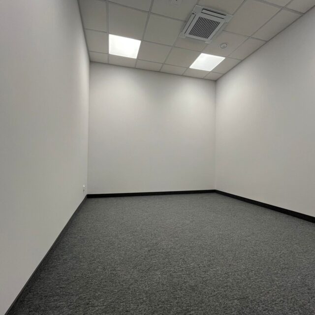 Puste pomieszczenie biurowe z wykładziną i sufitem podwieszanym w realizacji 7R Barniewice.