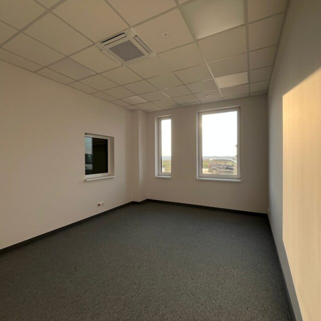 Pomieszczenie biurowe z dwoma oknami i wykładziną wykonane w projekcie 7R Barniewice.