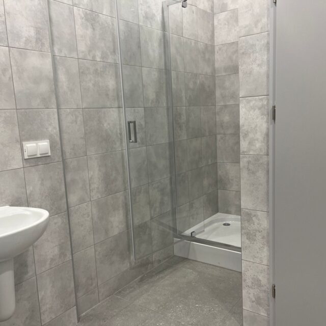 Kabina prysznicowa oraz umywalka wykończone w strefie sanitarnej projektu 7R Barniewice.