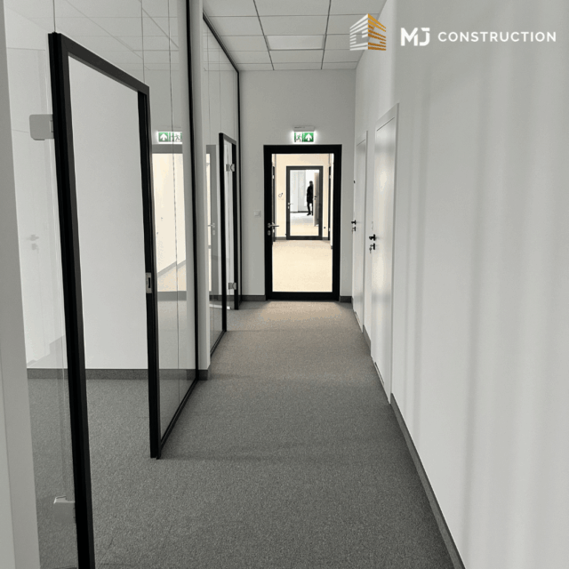 Korytarz w przestrzeni biurowej CEFEA z przeszklonymi pomieszczeniami i wyjściem ewakuacyjnym